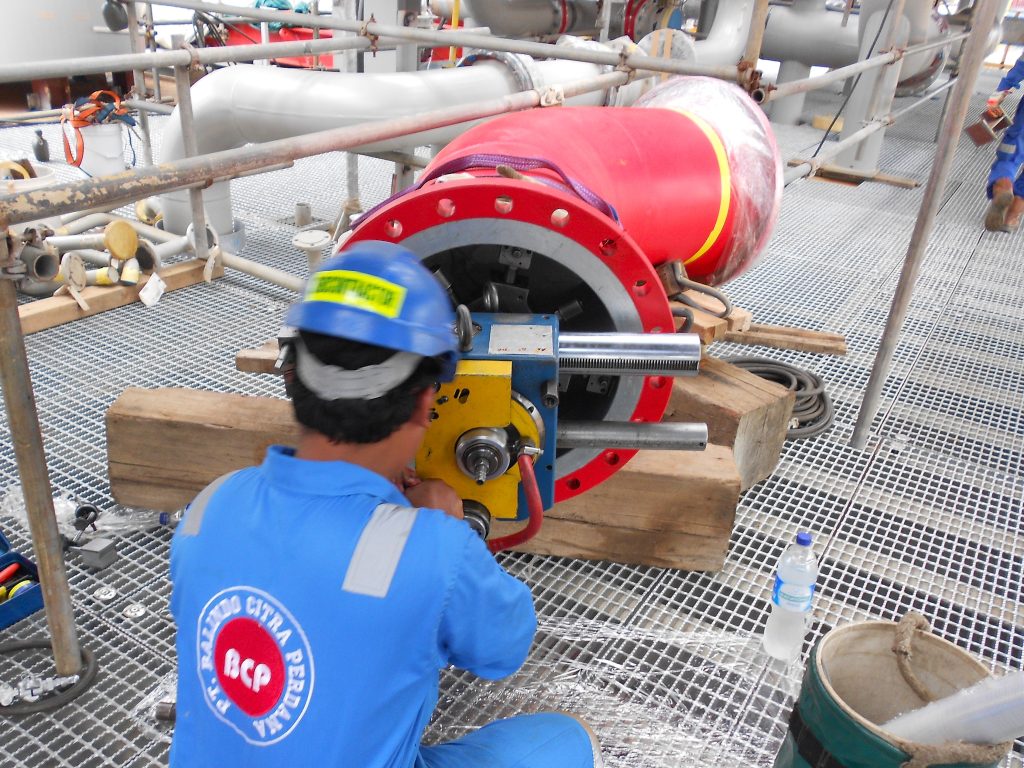 Worker performing flange facing with portable machine on site